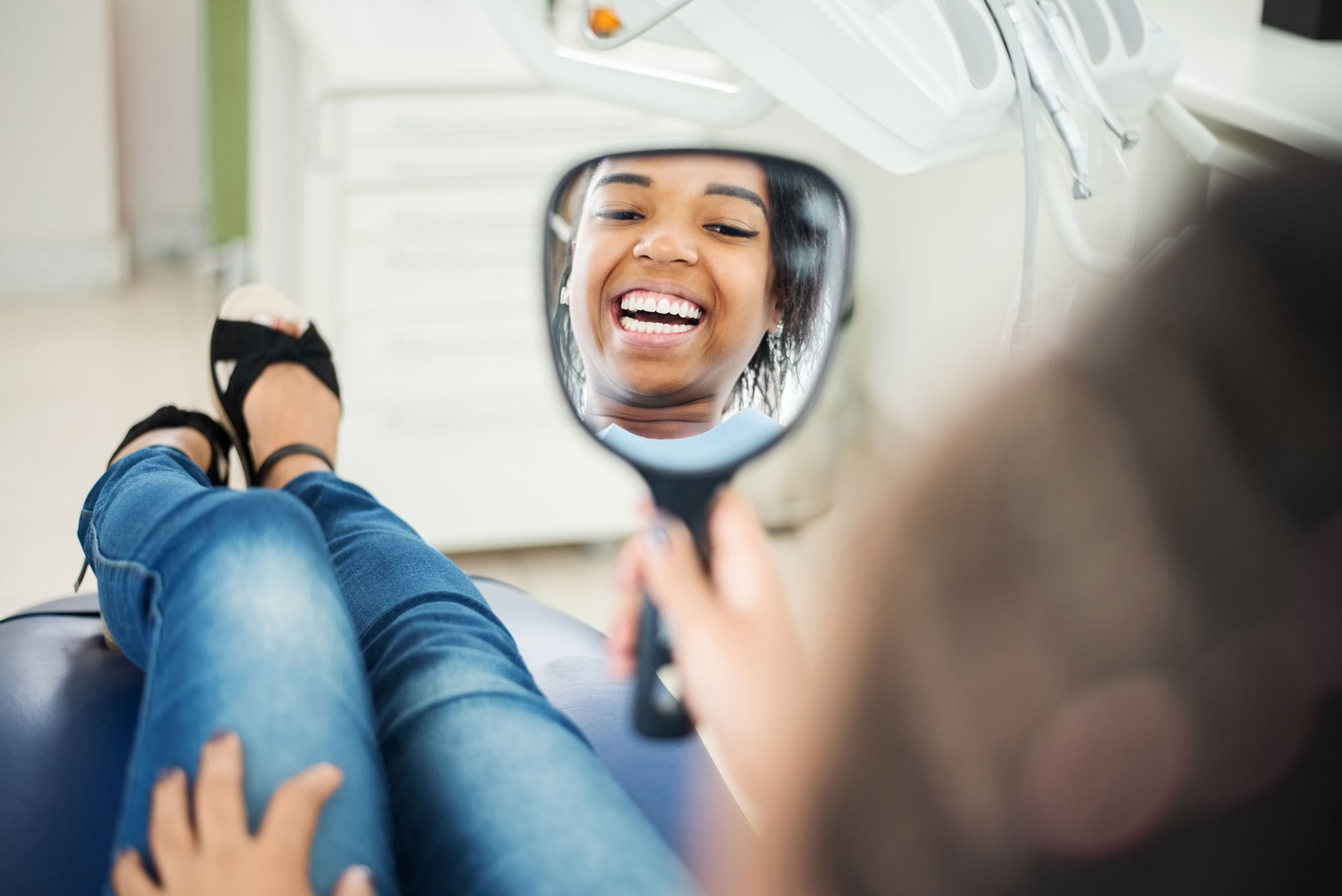 Patient hos tandläkare som ser sig i spegeln och ler